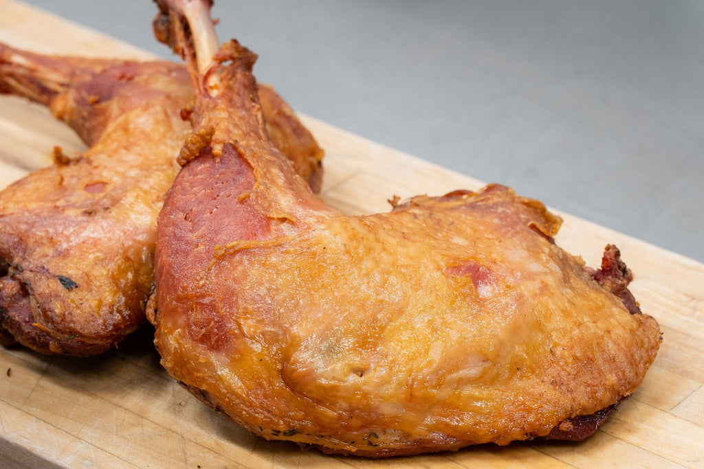 Two crispy fried chicken legs on a wooden cutting board.