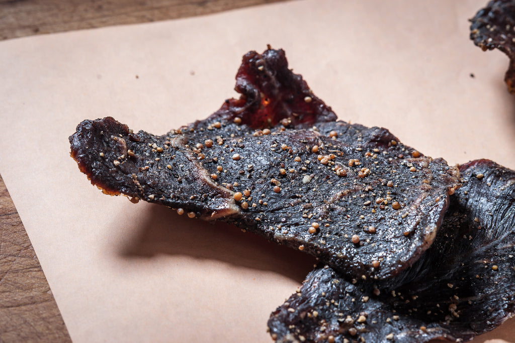 Close-up of seasoned beef jerky on parchment paper.