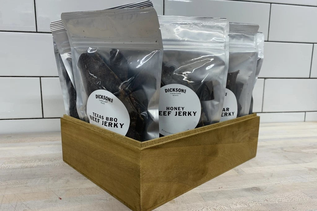 A box containing multiple packets of beef jerky on a wooden surface.
