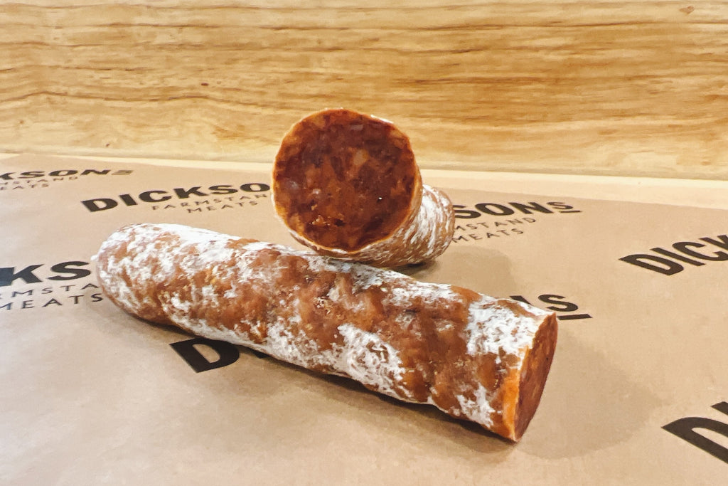 Two pieces of cured sausage on branded paper.