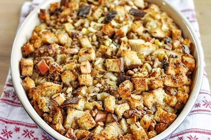 A baked dish of bread pudding with apples and nuts.