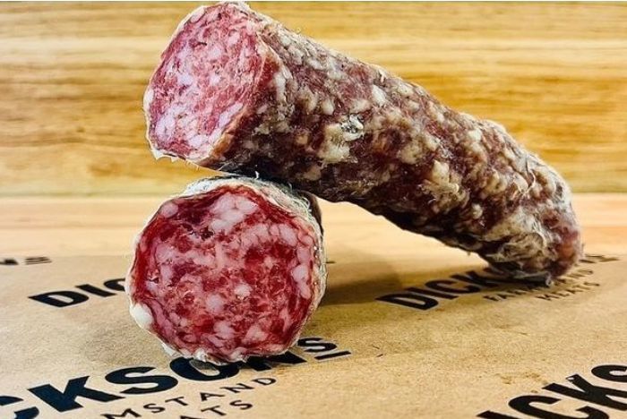 Sliced and whole salami on a wooden background