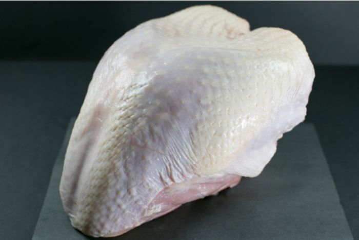 Raw turkey breast on a dark background.