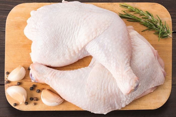 Raw chicken thighs on a wooden cutting board with garlic and herbs