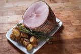 Sliced ham with roasted potatoes and herbs on a white plate